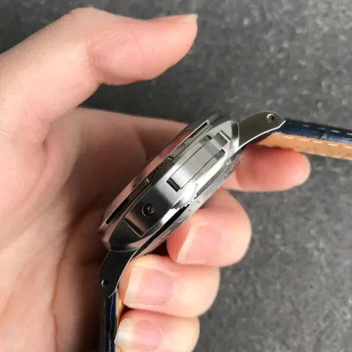 Crown guard and lever in profile, watch gripped by two fingertips