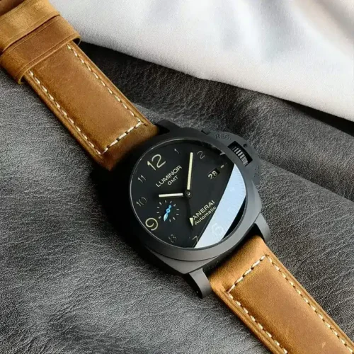 Watch laid diagonally on grey cloth, caramel strap with cream stitching