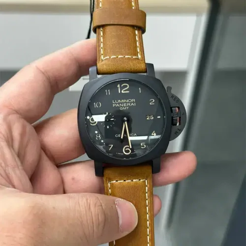 Held in the hand under shop lights, black dial with beige numerals