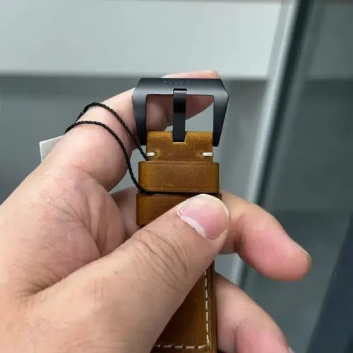 Black pin buckle on the tan strap, tag cord still attached