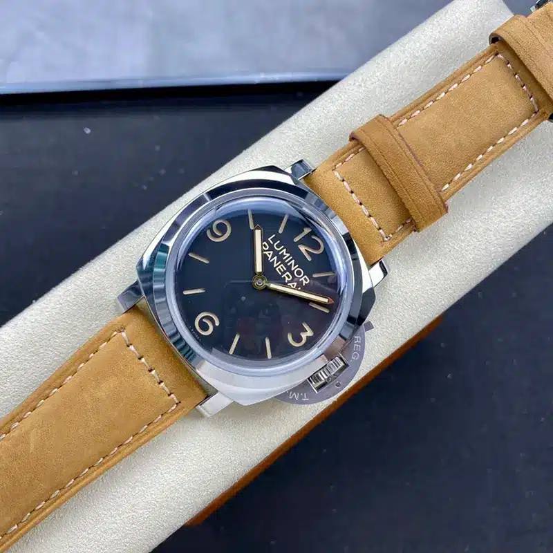 Watch resting on a cream stand, tan strap wrapped around it