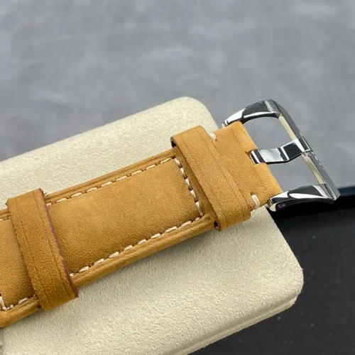 Polished pin buckle and two strap keepers on a cream cushion