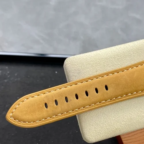 Tan strap end with stitched edges draped over a cream stand