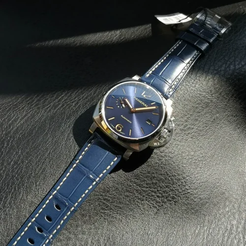 Navy croc-pattern strap with cream stitching laid across sunlit leather