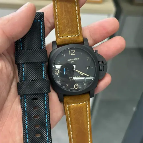 Tan leather fitted, spare black strap with sky blue thread held alongside