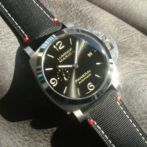 Sunlit black dial, beige hour numerals and red thread at the lugs