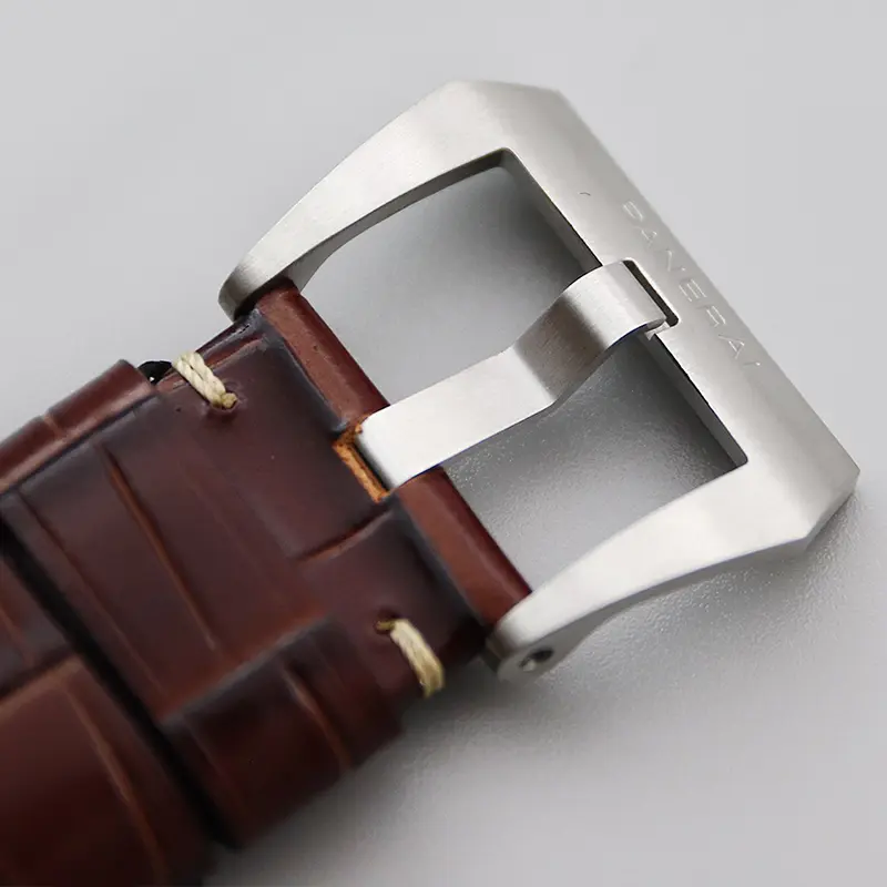 Brushed pin buckle threaded through the brown strap with cream stitching
