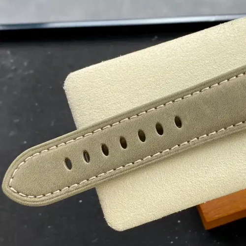 Olive suede strap tip with beige stitching across a cream pad