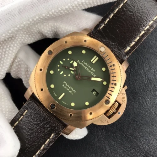 Olive dial rotated clockwise between gloved fingers, crown guard toward the bottom