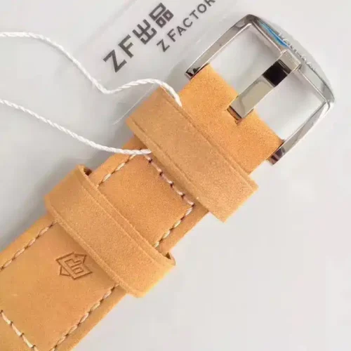 Polished tang buckle threaded through the caramel strap, white tag string