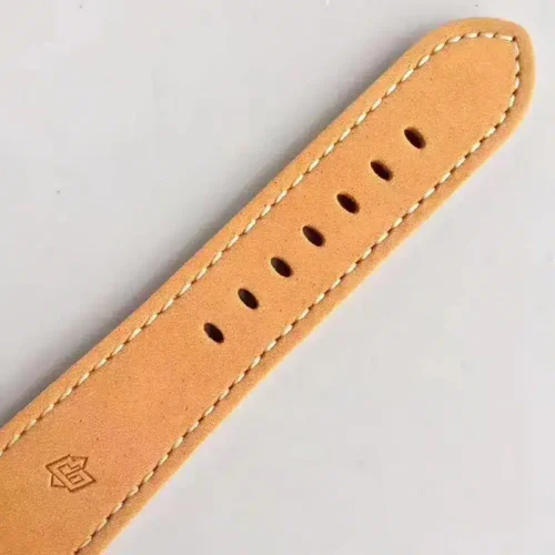 Tan strap end with cream stitching, punched holes and a pressed logo