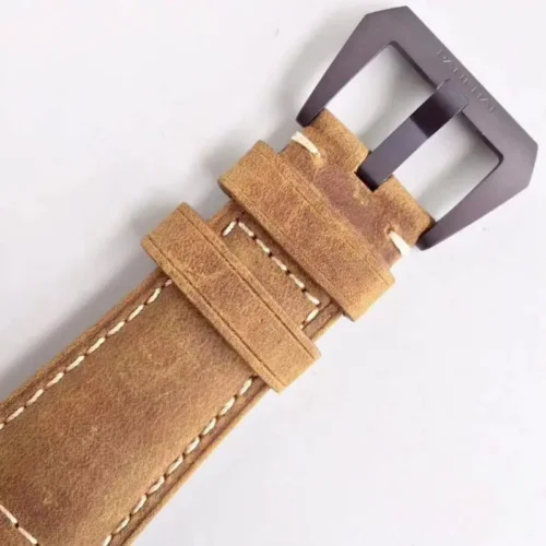 Dark brown pin buckle and two keepers on the worn tan leather strap