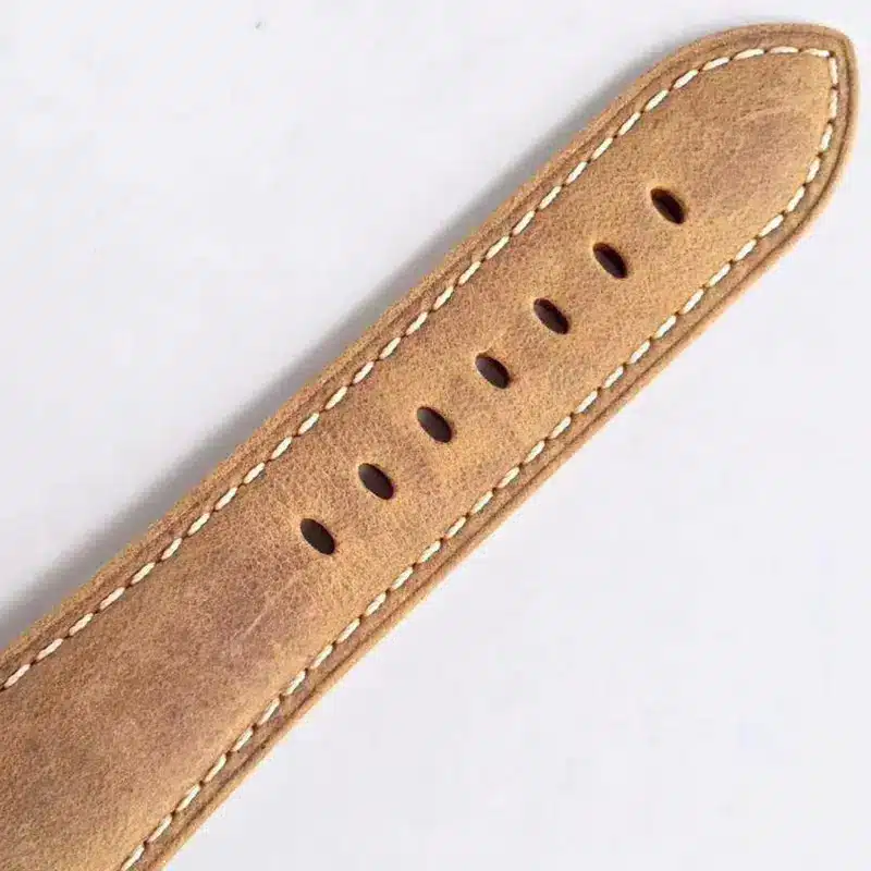 Distressed light brown leather tail, pale thread along the edge and holes