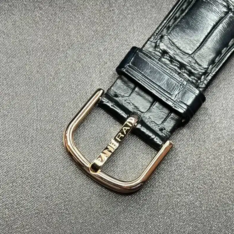 Rose gold tone pin buckle on a dark blue croc-pattern strap