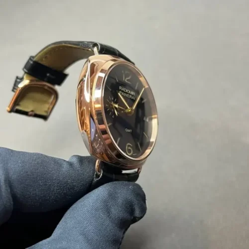 Crown side of the rose gold tone case held in a blue glove