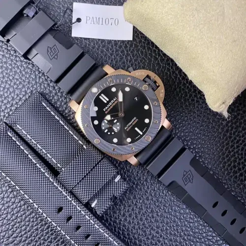 Watch beside a spare black textile strap with white stitching and a reference tag