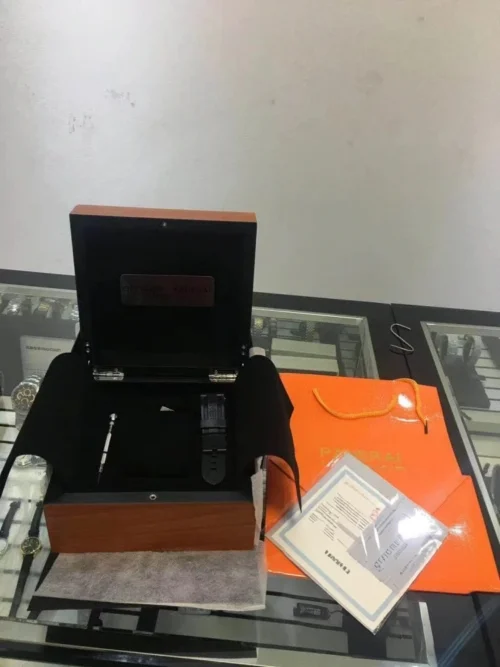 Open Panerai style wooden box with black lining, a strap and small screwdriver inside